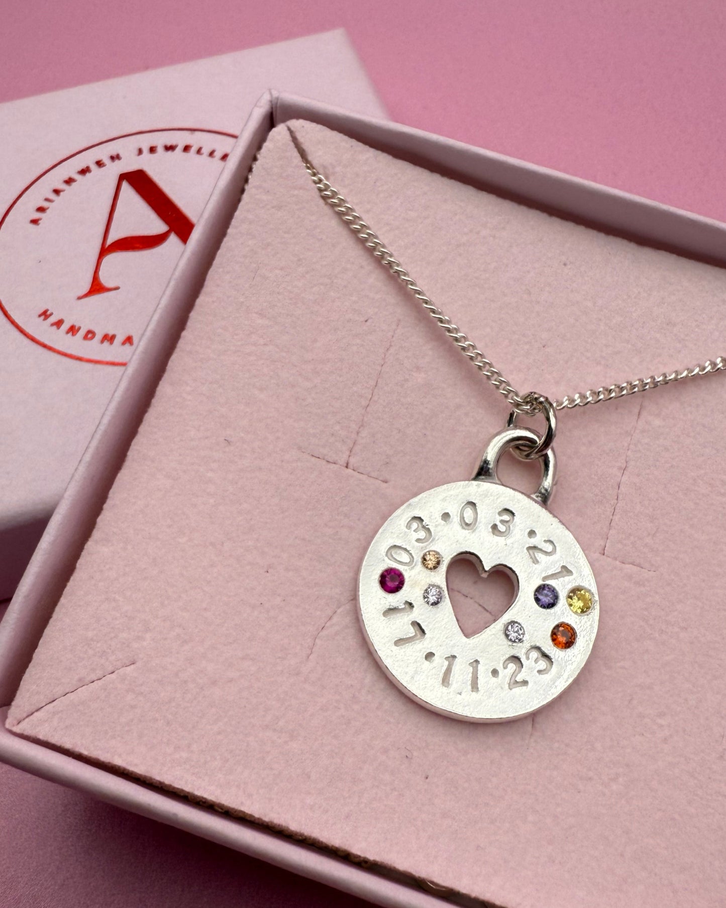 Necklace with a heart-shaped pendant in a pink box on a pink background