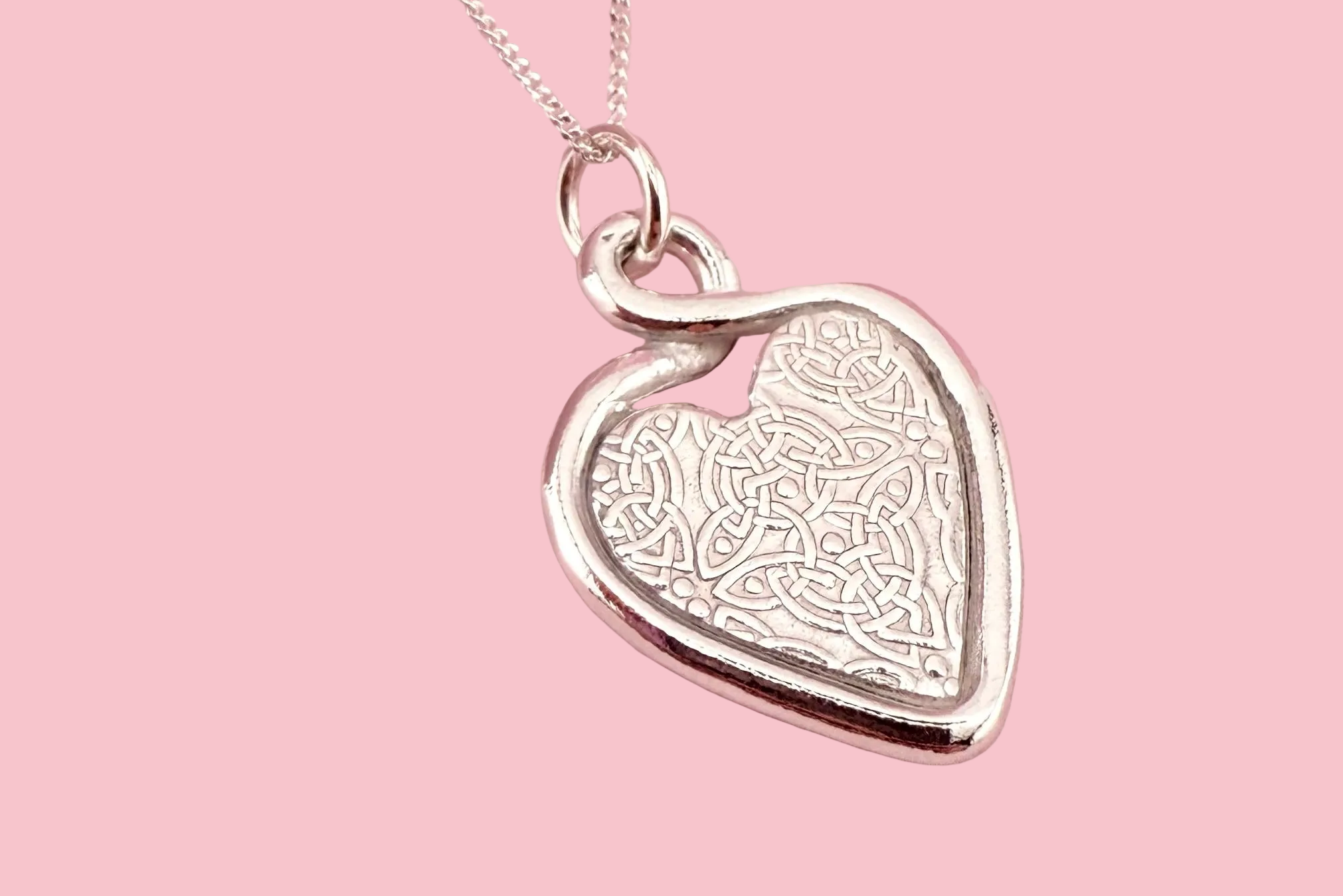 Silver heart-shaped pendant on a pink background