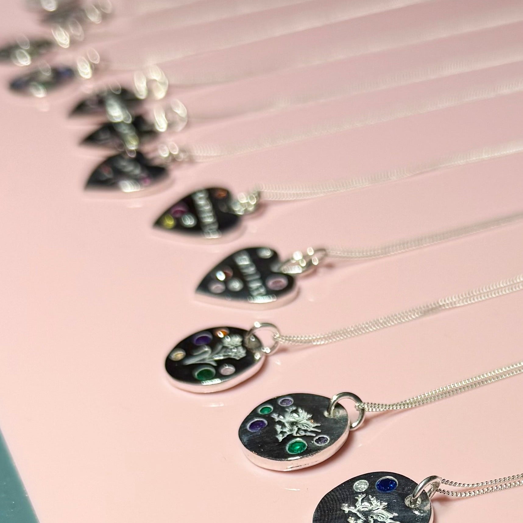 Necklaces with round pendants on a pink surface