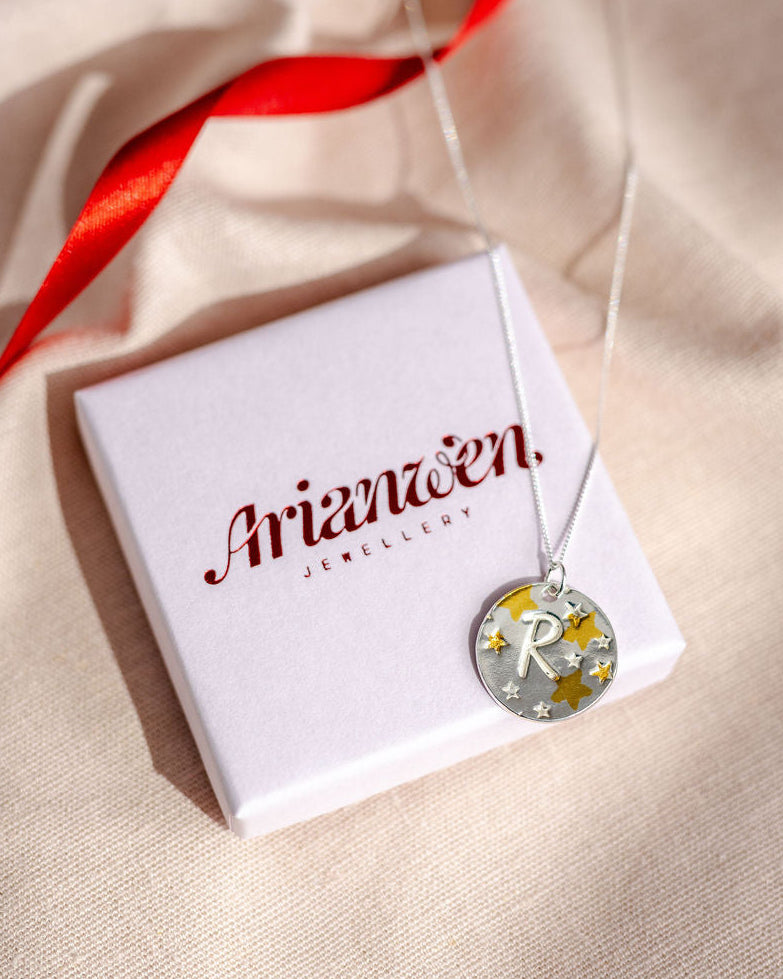 Mixed metal initial pendant featuring gold and hand stamped stars
